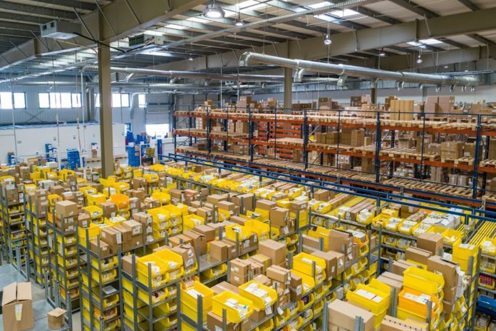 Distribuční sklad s regály a žlutými přepravkami se zbožím
