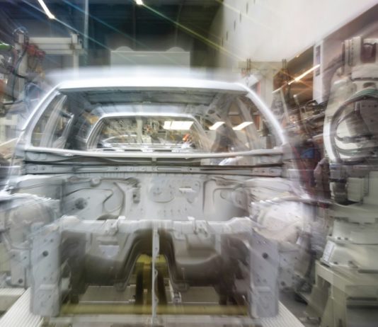 Audi v Ingolstadtu zkouší humanoidní roboty na řazení dílů k montáži Karoserie automobilu na montážní lince obklopená průmyslovými roboty