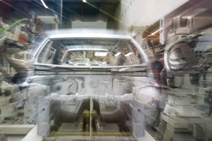 Audi v Ingolstadtu zkouší humanoidní roboty na řazení dílů k montáži Karoserie automobilu na montážní lince obklopená průmyslovými roboty