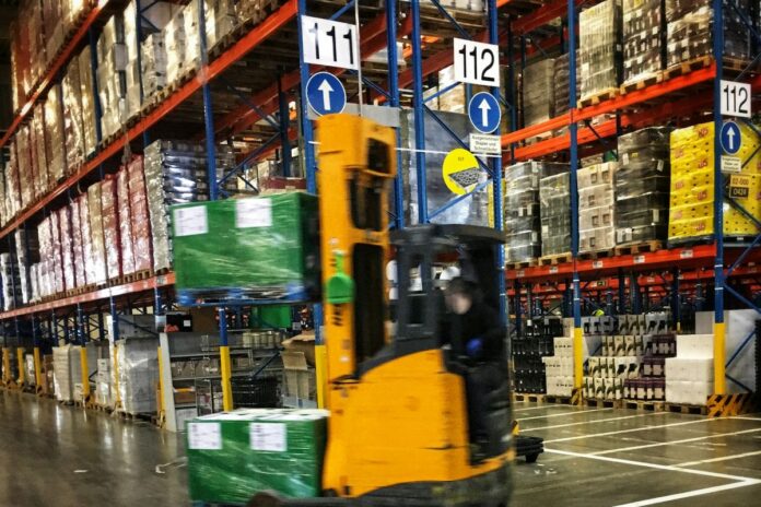 Vysokozdvižný vozík převáží palety mezi regály v logistickém skladu