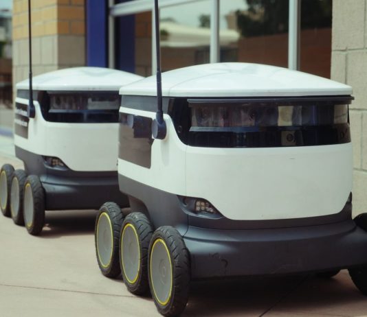 Téměř polovina profesionálních robotů míří do logistiky Dva autonomní doručovací roboti stojí na chodníku u budovy
