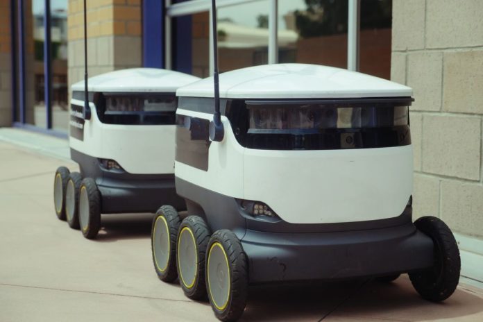 Téměř polovina profesionálních robotů míří do logistiky Dva autonomní doručovací roboti stojí na chodníku u budovy
